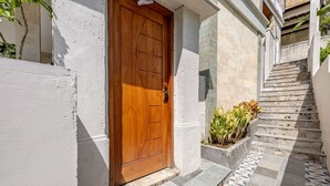 A wooden door, a white wall, a stone staircase, and a planter with plants. - Widhiana Villa Ubud (Ubud)