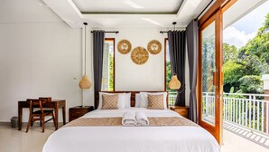 A bedroom with a bed, a desk, a chair, and a balcony with a view of greenery. - Widhiana Villa Ubud (Ubud)