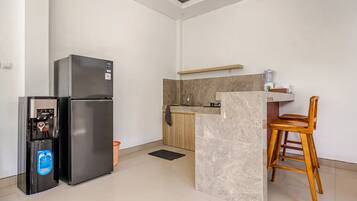 Una cocina moderna con refrigerador, dispensador de agua, una silla de madera y encimera de mármol.