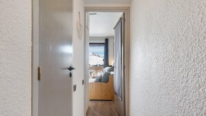 A narrow hallway leading to a room with a bed, a window, and a view of a snowy landscape. - Cozy Ski-In/Ski-Out Studio 26 m² – Alpe d’Huez (Huez)