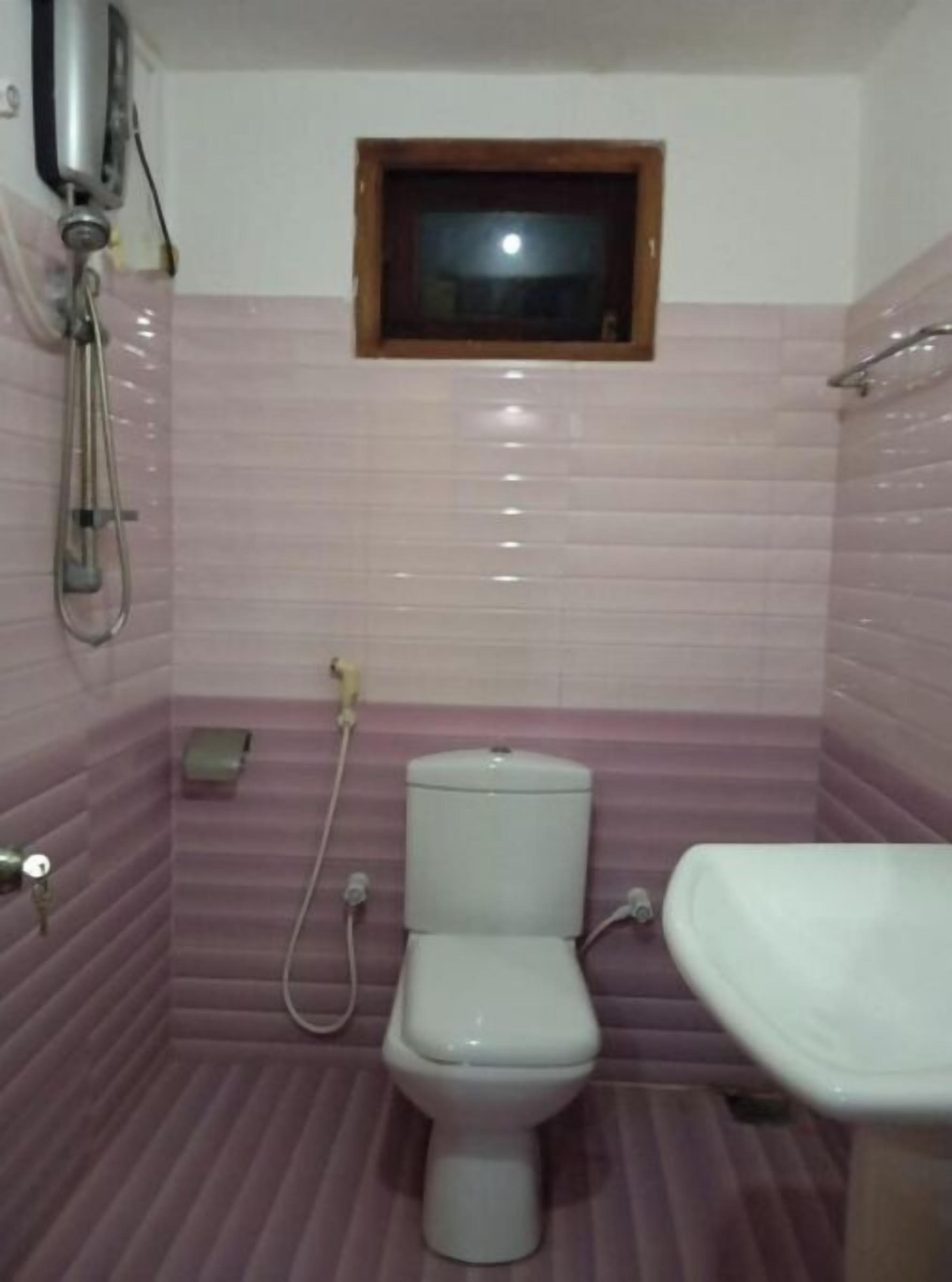 Un baño con inodoro, bidé y ventana sobre el inodoro.