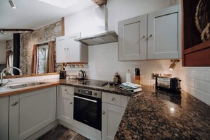 Eine Küche mit weißen Schränken, einer Granitabdeckung, einem eingebauten Backofen und einer Steinwand.