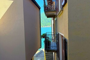 Rua estreita com varandas, vista clara do mar e um edifício com fachada amarela.
