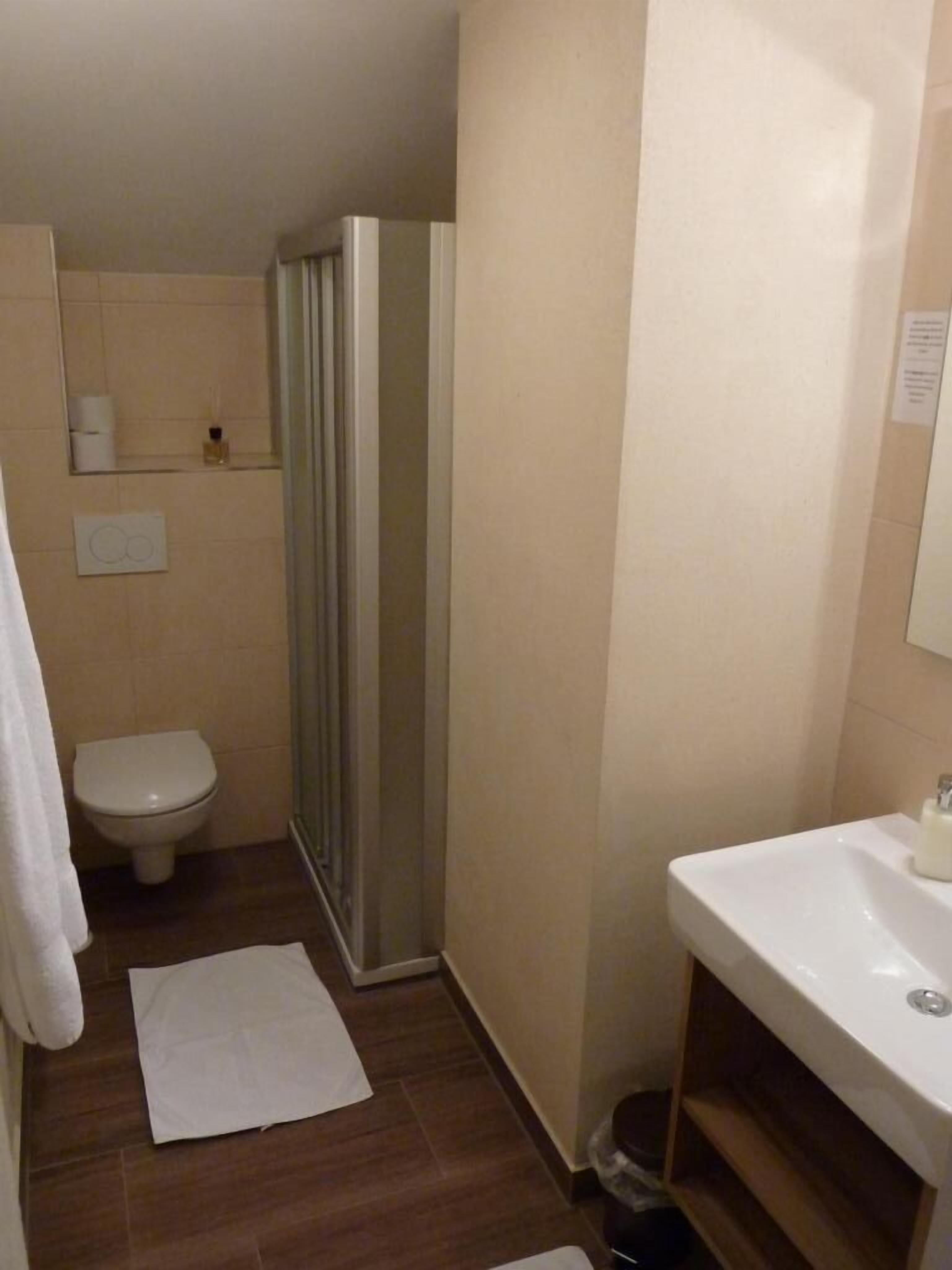 A small bathroom with a toilet, shower, and sink.