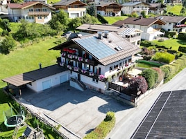 Um edifício de dois andares com telhado inclinado, varanda frontal coberta e garagem.