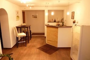 Espaço compacto com área de refeições, cozinha compacta e geladeira.