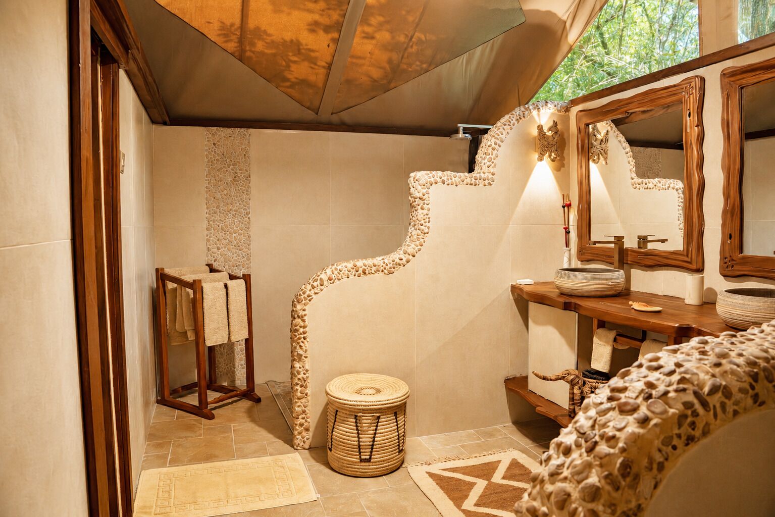Baño con pared de piedra, tocador de madera y espejo con marco de madera.