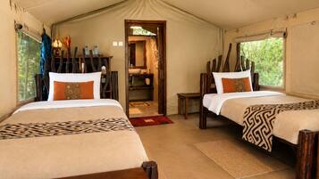 A tented accommodation with two beds, a bathroom, and a view of greenery.
