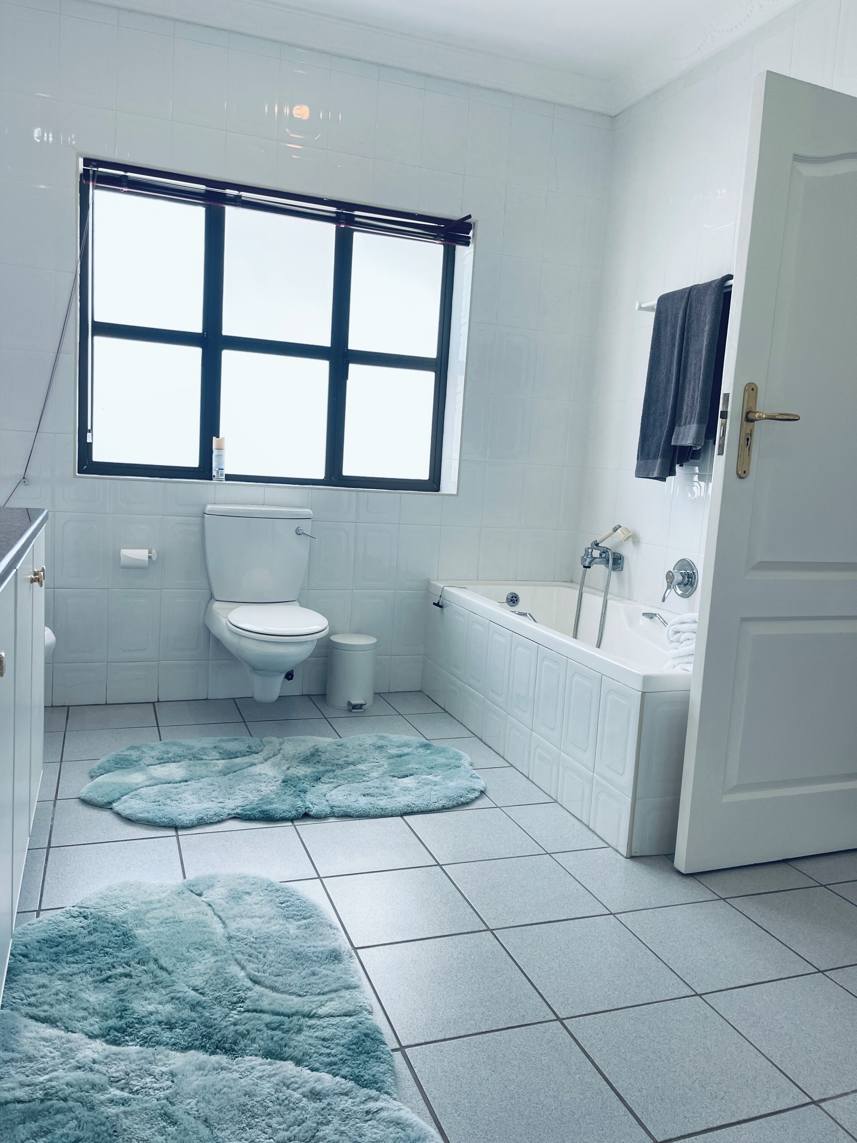 A bathroom with a toilet, sink, bathtub, and a window.
