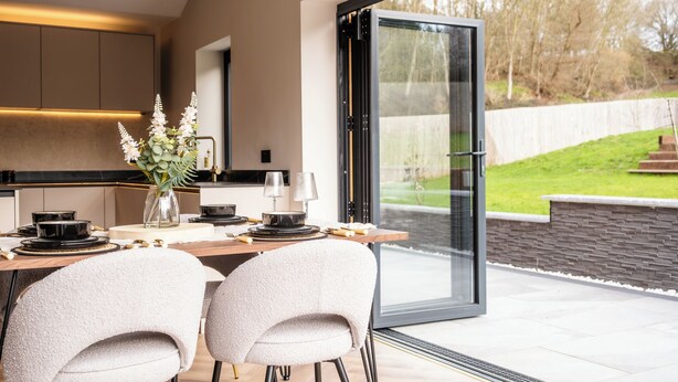 A modern kitchen with a dining area, large glass doors, and a view of the outdoors. - Megan's Hideaway Luxury 4 Bed Retreat (Stourport-on-Severn)