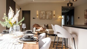 A modern dining area with a wooden table, white chairs, and a vase of flowers. - Megan's Hideaway Luxury 4 Bed Retreat (Stourport-on-Severn)