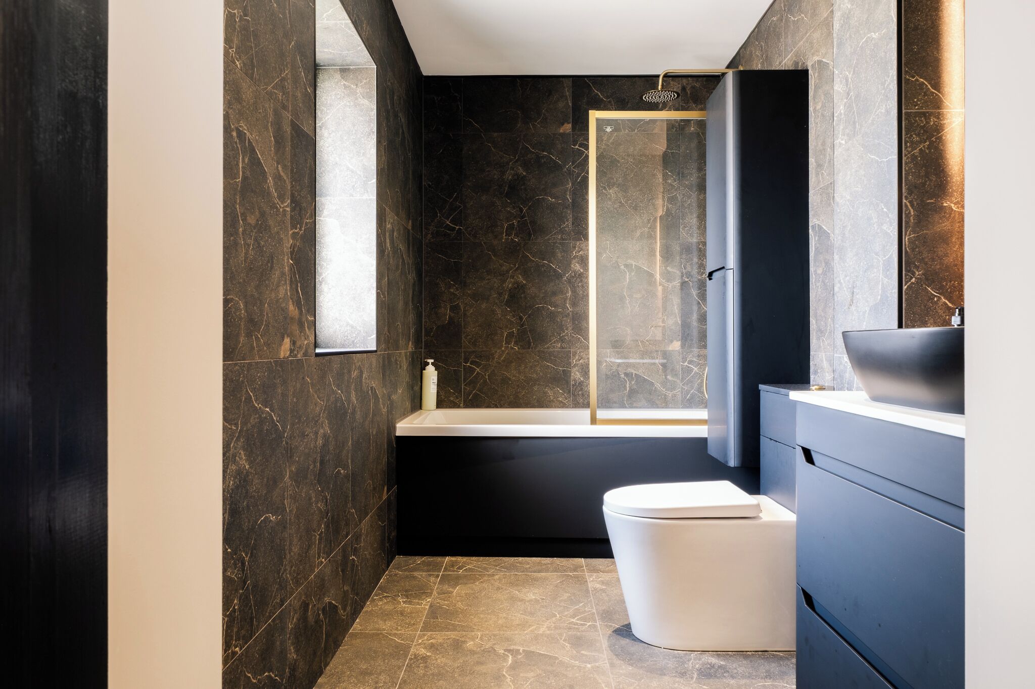 A modern bathroom with a bathtub, toilet, and vanity.