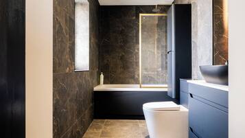 A modern bathroom with a bathtub, toilet, and vanity.