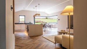 A modern kitchen with a central island, a dining area with chairs, a sofa, and a lamp. - Megan's Hideaway Luxury 4 Bed Retreat (Stourport-on-Severn)