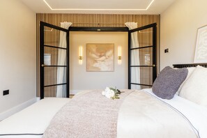 A bedroom with a bed, a wall-mounted artwork, and a decorative wall panel. - Megan's Hideaway Luxury 4 Bed Retreat (Stourport-on-Severn)