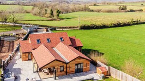A modern house with a red roof, a patio area, and a view of the surrounding countryside. - Megan's Hideaway Luxury 4 Bed Retreat (Stourport-on-Severn)