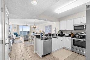 A modern kitchen with white cabinets, stainless steel appliances, and a large island. - FAMILY FUN! Oceanfront 2 Bedrooms. Great amenities/location! (North Myrtle Beach)