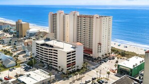 A high-rise hotel with multiple floors, a parking garage, and a view of the beach. - 20% off 3-7 thru Dec. Oceanfront 2BR 2BA. Crescent Shores. Views!! Amenities!! (North Myrtle Beach)