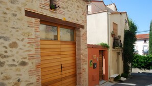 Un bâtiment avec une façade en pierre, une porte de garage en bois et une petite porte d’entrée.
