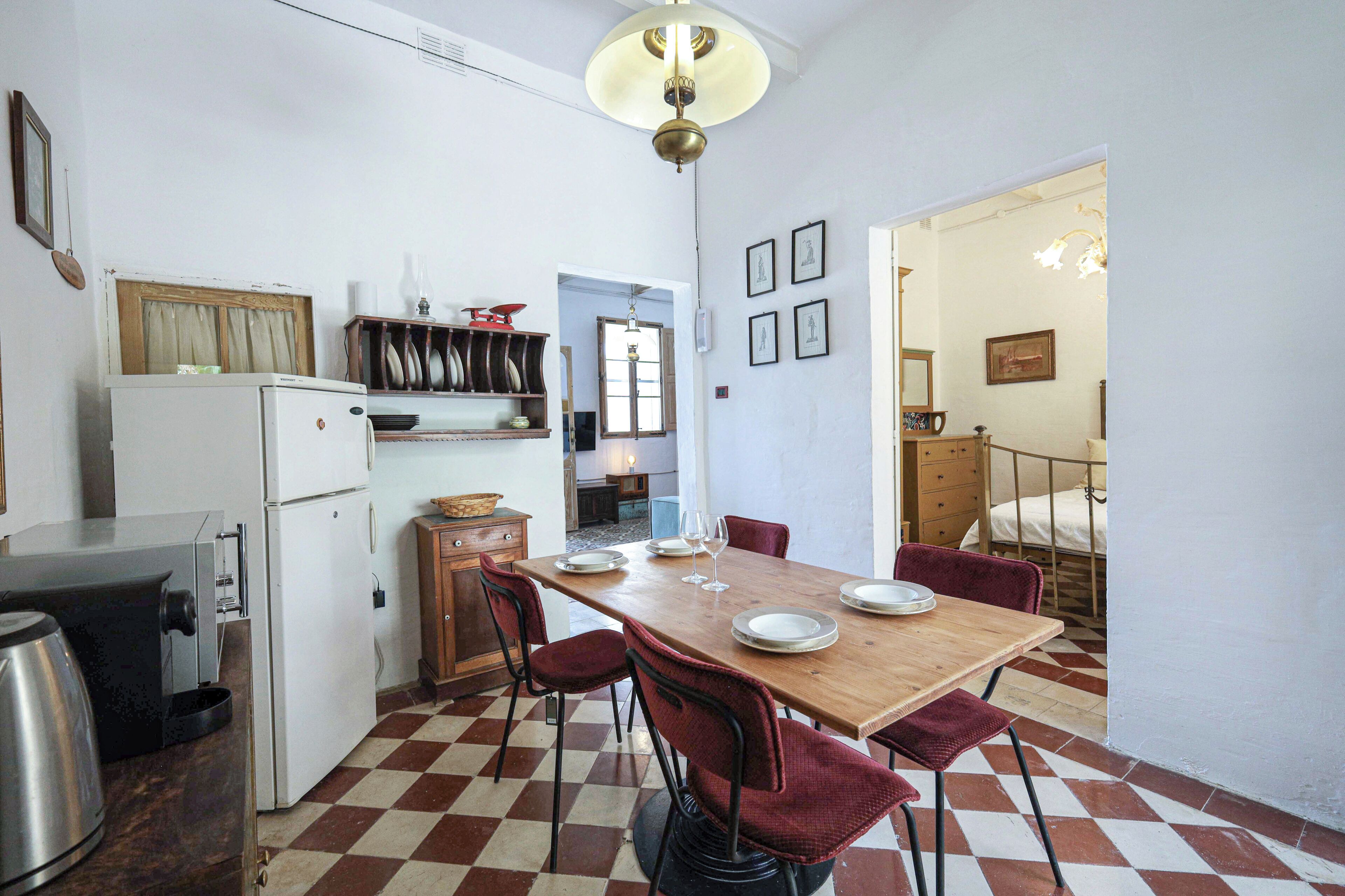 Cocina compacta con una mesa de madera lista para comer, un refrigerador y una cafetera.