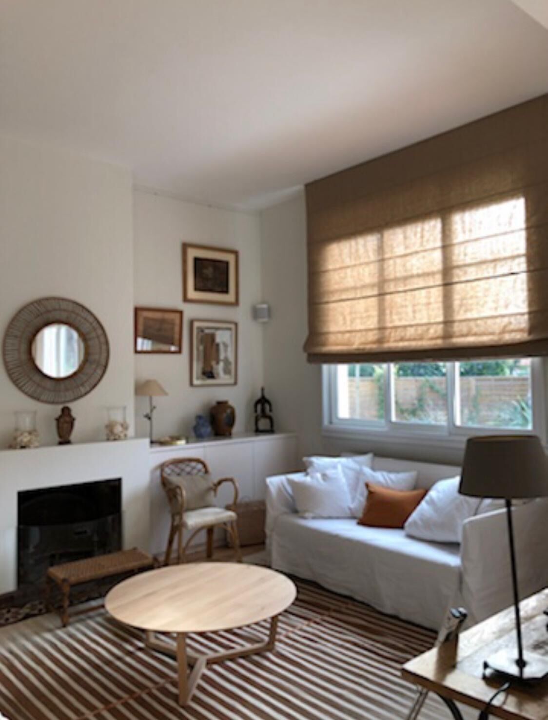 Ein Wohnzimmer mit Kamin, einer Couch, einem runden Tisch und einem Fenster mit Jalousien.