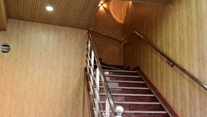 Una escalera con paneles de madera y barandillas de metal que conduce a un piso superior.