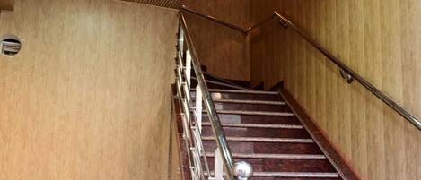 A staircase with wooden paneling and metal railings, leading to an upper floor.