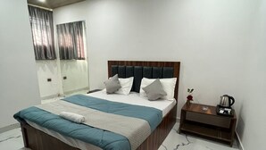 Un dormitorio con cama, mesita de noche, espejo e iluminación empotrada en el techo.