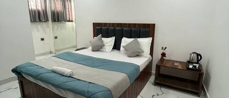 A bedroom with a bed, a nightstand, a mirror, and a ceiling with recessed lighting.