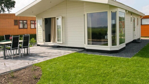 A modern house with a patio, a dining area, and a large sliding glass door. - Chalet With 3 Bedrooms and Infrared Sauna (West-Graftdijk)