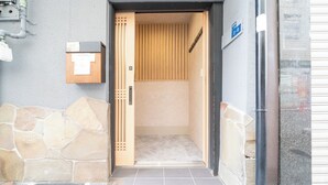 Ingresso di un edificio con parete in pietra, porta in legno e pavimento piastrellato.