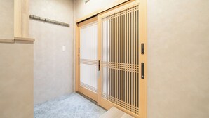 Una stanza tradizionale giapponese con pavimento in tatami, uno schermo scorrevole con motivo a reticolo e un piccolo tavolo in legno.