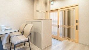 Una stanza con un tavolo, sedie, un armadio e una porta scorrevole con decorazioni a griglia in legno.