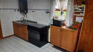 A kitchen with a stove, oven, microwave, and wooden cabinets.
