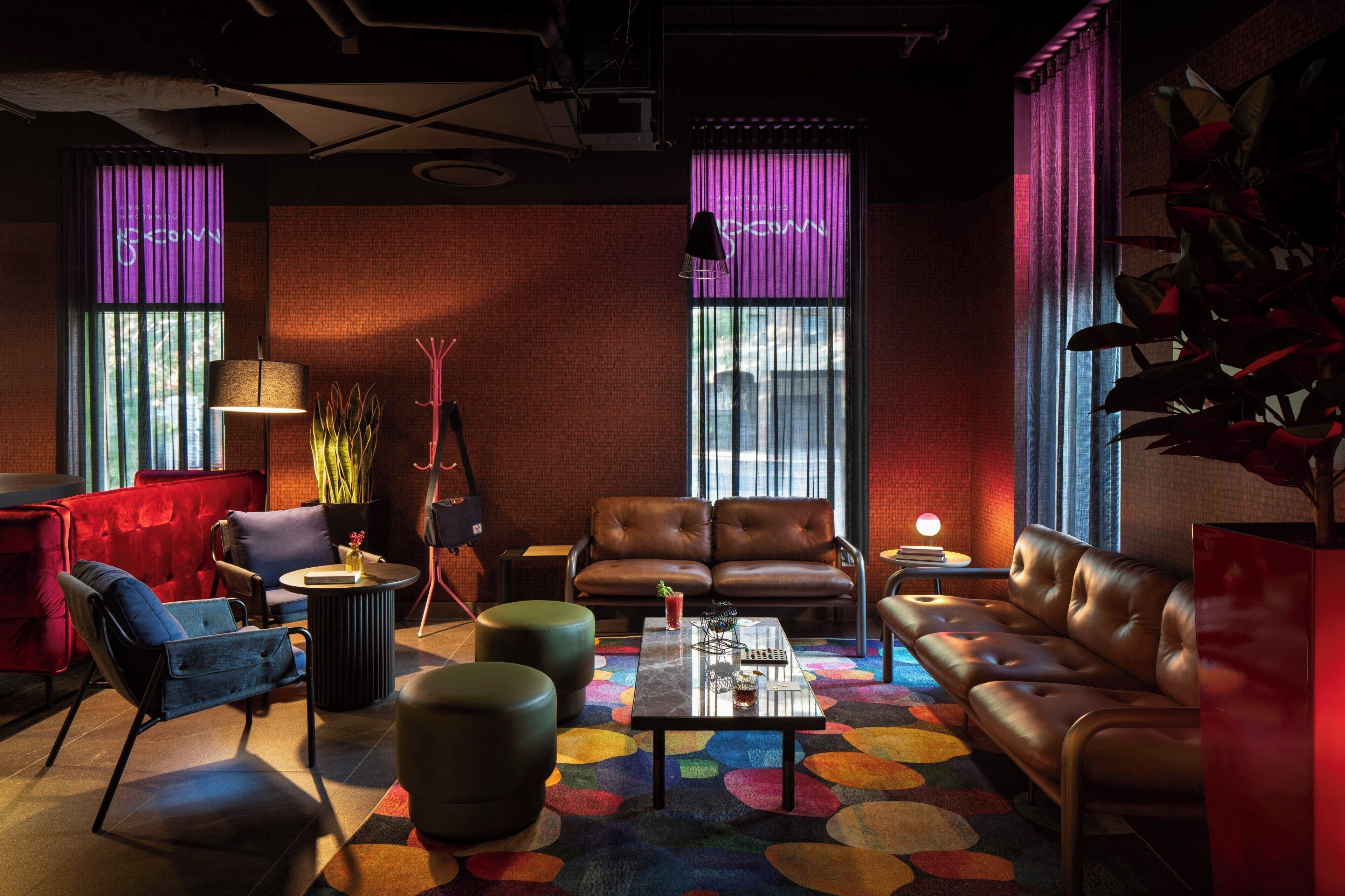 A modern lounge area with leather sofas, a coffee table, and a colorful abstract carpet.