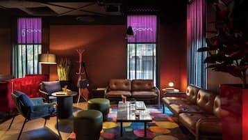 A modern lounge area with leather sofas, a coffee table, and a colorful abstract carpet.