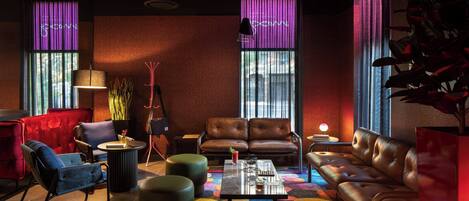 A modern lounge area with leather sofas, a coffee table, and a colorful abstract carpet.