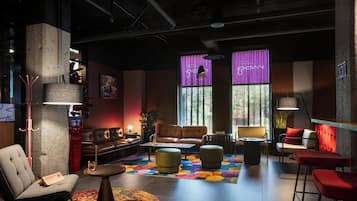 A modern lounge area with leather sofas, a colorful rug, and a mix of seating options including a bar stool and a high chair.