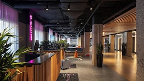 A hotel lobby with a reception desk, seating area, and a view of the street. - Moxy Ottawa Downtown (OTTAWA)