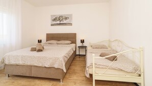 A bedroom with two beds, a bedside table, a lamp, and a painting on the wall. - Stylish vacation apartment in Dramalj - beach just 250 m away (Dramalj)