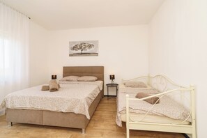 A bedroom with two beds, a bedside table, a lamp, and a painting on the wall. - Stylish vacation apartment in Dramalj - beach just 250 m away (Dramalj)