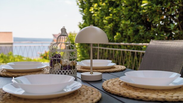 A table set with plates and a lamp, with a view of the sea and greenery in the background. - Stylish vacation apartment in Dramalj - beach just 250 m away (Dramalj)