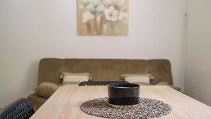 A dining table with a decorative item, a brown couch, and a painting on the wall. - Stylish vacation apartment in Dramalj - beach just 250 m away (Dramalj)