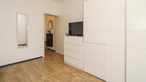 A hallway with a wooden floor, a white wardrobe, a small mirror, and a television on a stand. - Stylish vacation apartment in Dramalj - beach just 250 m away (Dramalj)