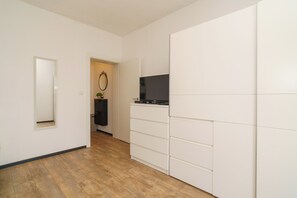 A hallway with a wooden floor, a white wardrobe, a small mirror, and a television on a stand. - Stylish vacation apartment in Dramalj - beach just 250 m away (Dramalj)