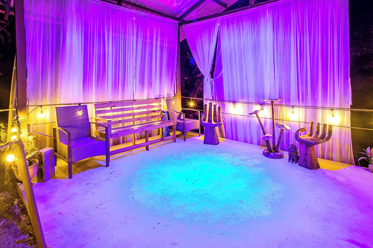 An outdoor seating area with a bench, chairs, and decorative lighting.