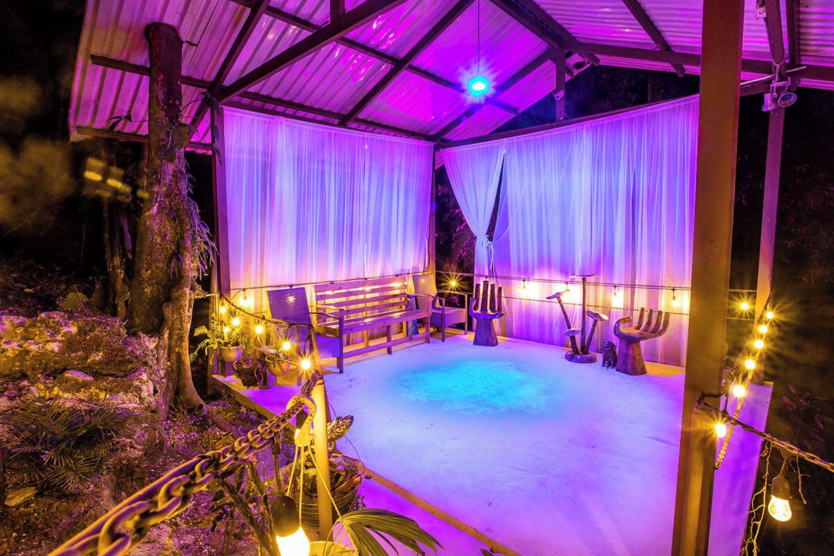 An outdoor covered area with a seating arrangement, string lights, and a central light fixture.