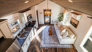 Um loft moderno com cozinha, sala de estar e uma grande janela.