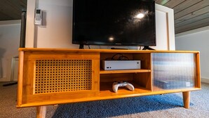 Centro de entretenimento em madeira com televisão, console de jogos e leitor de DVD.