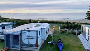 Un campeggio con camper, un kayak e vista sulla spiaggia.